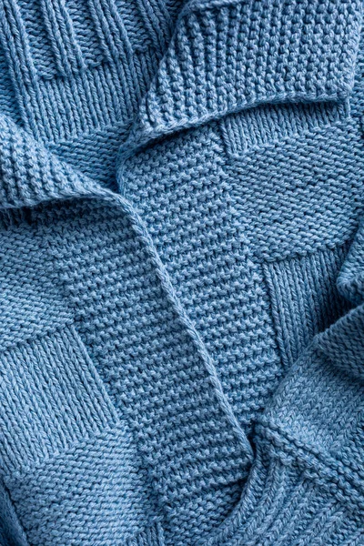 Close up view of handemade knitted blue women jumper with polo collar. Stylish cotton pullover with chess texture pattern and long sleeves front view. Above shot