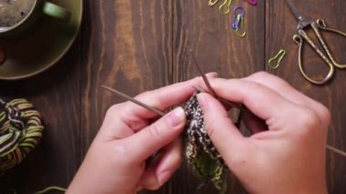 Dümdüz uzanmış, kadın elleri yeşil çorap örüyor. Ahşap masa ve bir fincan kahveyle rahat bir atmosfer. Tam HD görüntü videosu