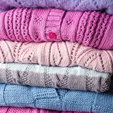 Katlanmış el yapımı kazak yığınının yakın görüntüsü. Ev yapımı, renkli, kendi ellerimle ördüğüm kıyafetler.