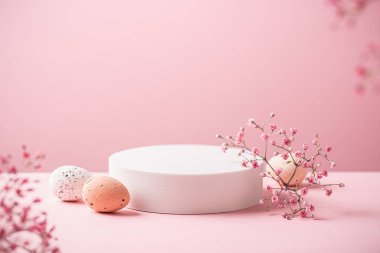 Abstract empty white podium with Easter quail eggs and spring flowers on pink background. Mock up stand for product presentation. Minimal concept. Advertising template