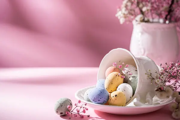 白瓷咖啡杯 有五彩缤纷的鹌鹑蛋和粉色背景的春花 春假和复活节假期的概念 带有复制空间 免版税图库图片