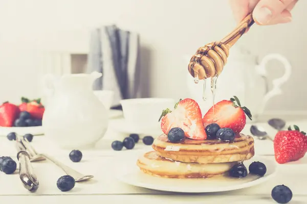 健康早餐的概念 自制煎饼草莓 蓝莓和蜂蜜 复古风格色调 图库图片