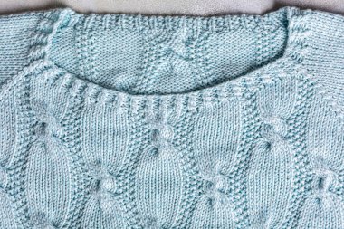 Kablolu süveter için turkuaz örgü desenli bir arka plan. Yaka çizgisinin yukarısında. Örgü kıyafetlerinin en üst görünümü