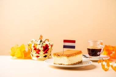 Tahta tahtanın üzerinde küçük bir Hollanda bayrağı olan kırmızı, beyaz ve mavi parçalarla kaplı portakallı tompet ve donut yığını. Ulusal Bayram Koningsdag 27 Nisan 'da Hollanda' da