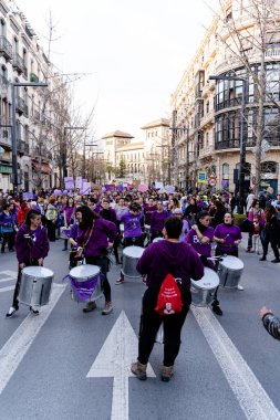 Mor giyinmiş bir grup insan, İspanya 'nın Granada kentinin sokaklarında düzenlenen Uluslararası Kadın Günü gösterisinde batucada' yı davullarla protesto ediyorlar.