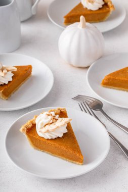 Slices of traditional pumpkin pie in a modern light and bright setting