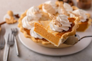 Pumpkin cheesecake swirl pie topped with whipped cream with a slice taken out, original Thanksgiving dessert idea