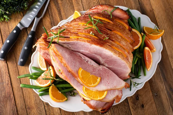 Christmas honey orange glazed ham served on a plate with green beans overhead view