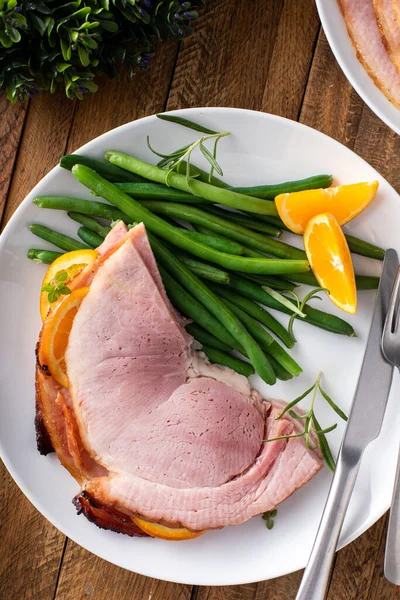 Christmas honey orange glazed ham served on a plate with green beans
