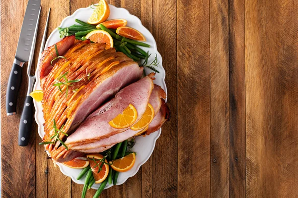 Christmas honey orange glazed ham served on a plate with green beans overhead view with copy space