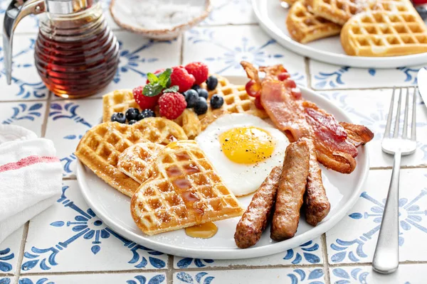 Breakfast plate with waffles, fried egg, bacon and sausage, filling and healthy breakfast