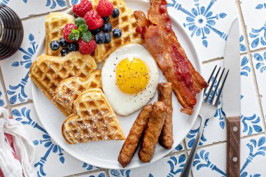 Waffle 'lı kahvaltı tabağı, sahanda yumurta, pastırma ve sosis, doyurucu ve sağlıklı kahvaltı.