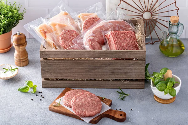 Meat delivery box, variety of meat chops and packages in a wooden crate, food subscription concept