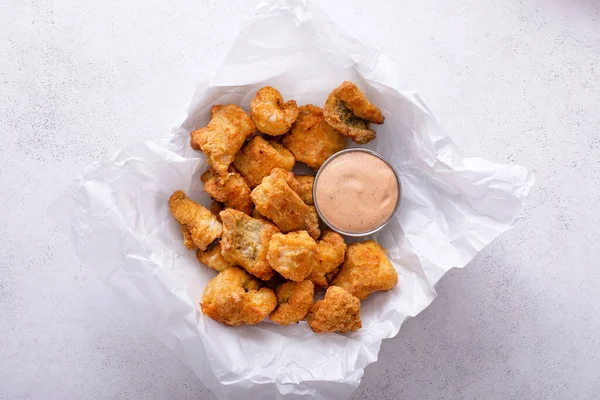 Fried catfish nuggets served with remoulade sauce on a plate with parchment paper