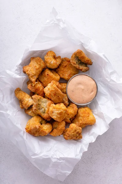 Fried catfish nuggets served with remoulade sauce on a plate with parchment paper