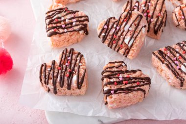 Heart shaped pink rice krispie treats for Valentines Day drizzled with dark chocolate