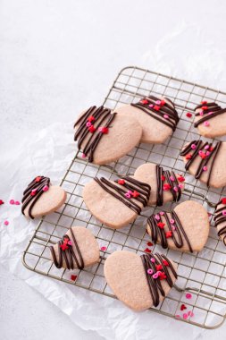 Heart shaped strawberry cut out cookies with dark chocolate glaze and sprinkles for Valentines day
