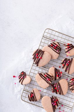 Heart shaped strawberry cut out cookies with dark chocolate glaze and sprinkles for Valentines day, copy space