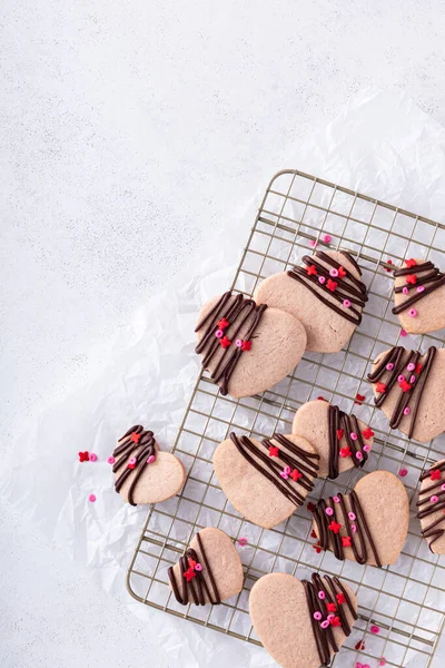 Heart shaped strawberry cut out cookies with dark chocolate glaze and sprinkles for Valentines day, copy space