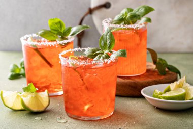 Strawberry basil margarita with lime wedges on the table, refreshing summer cocktail