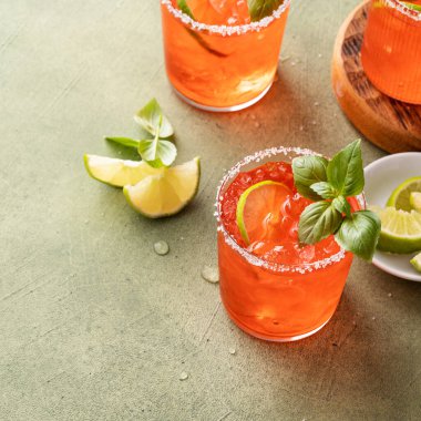 Strawberry basil margarita with lime wedges on the table, refreshing summer cocktail with copy space