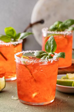 Strawberry basil margarita with lime wedges on the table, refreshing summer cocktail