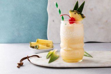 Tropical pina colada cocktail or mocktail in a tiki glass with pineapple and cherry with copy space