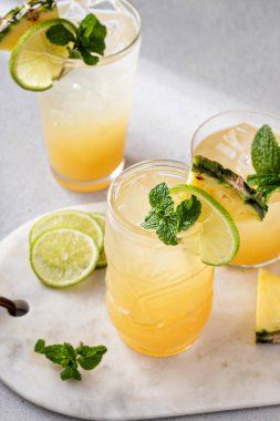 Mai tai cocktail in different glasses garnished with pineapple, lime and mint