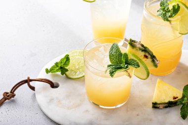 Mai tai cocktail in different glasses garnished with pineapple, lime and mint with copy space
