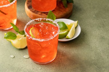 Strawberry basil margarita with lime wedges on the table, refreshing summer cocktail with copy space