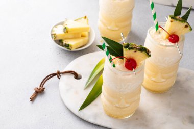 Tropical pina colada cocktail or mocktail in a tiki glass with pineapple and cherry