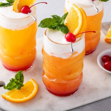 Zombie tropical cocktail with rum served in tiki glasses with orange slices and cherries