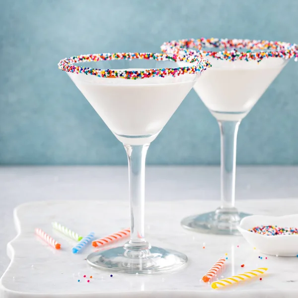 Birthday cake martini with sprinkles on the glass rim and birthday candles