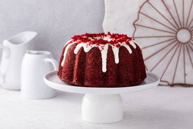 Red velvet bundt cake with cream cheese frosting and cake crumbs on top