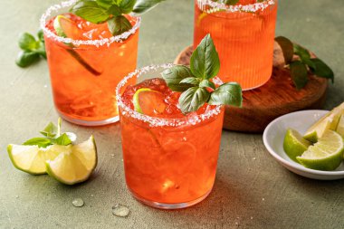 Strawberry basil margarita with lime wedges on the table, refreshing summer cocktail