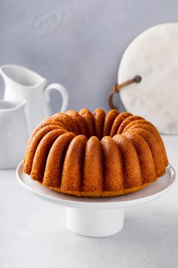 Vanilla bundt cake on a cake stand, golden freshly baked ready to eat
