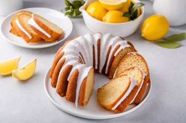 Lemon bundt cake drizzled with powdered sugar glaze topped with lemon zest sliced