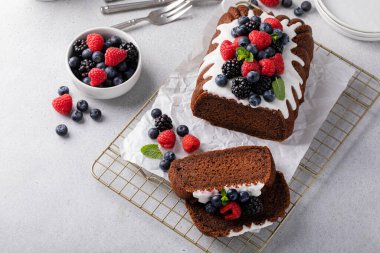 Chocolate pound cake topped with cream cheese glaze and fresh berries sliced