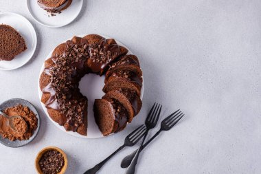 Chocolate cake baked in a bundt pan with chocolate ganache glaze and chocolate curls sliced overhead view with copy space