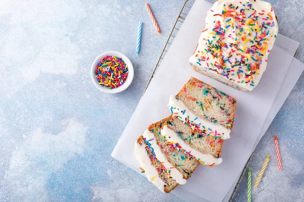 Birthday cake or funfetti pound cake with sprinkles and frosting sliced with birthday candles