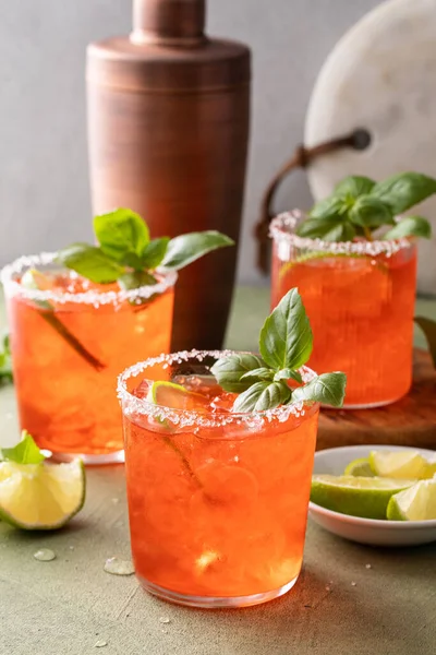 Strawberry basil margarita with lime wedges on the table, refreshing summer cocktail