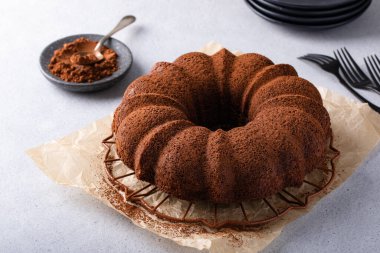 Chocolate bundt cake dusted with cocoa powder on a cooling rack