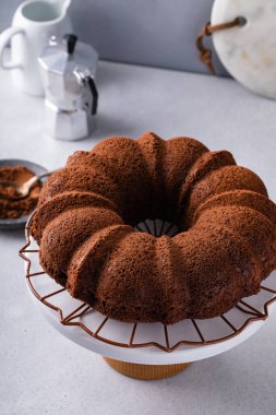 Chocolate bundt cake dusted with cocoa powder on a cooling rack