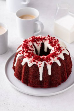 Red velvet bundt cake with cream cheese frosting and cake crumbs on top