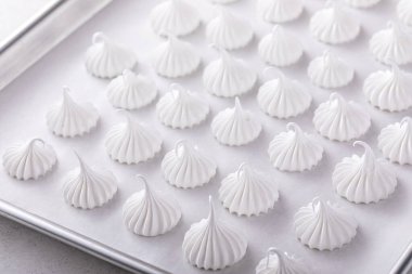 Meringue kisses on a baking sheet ready to be baked, homemade cookies idea