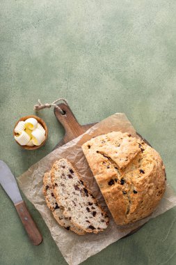 Soda bread in a cast iron pan with cranberries and pecans sliced and served with irish butter, irish recipe idea with St Patricks day