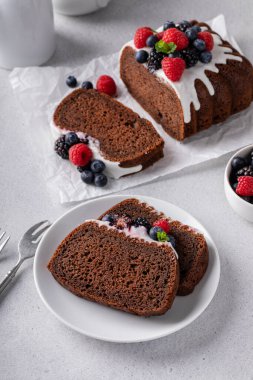 Chocolate loaf cake or quick bread topped with cream cheese glaze and fresh berries sliced