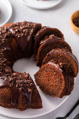 Chocolate cake baked in a bundt pan with chocolate ganache glaze and chocolate curls sliced