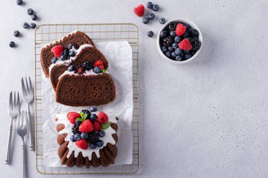 Chocolate pound cake topped with cream cheese glaze and fresh berries sliced