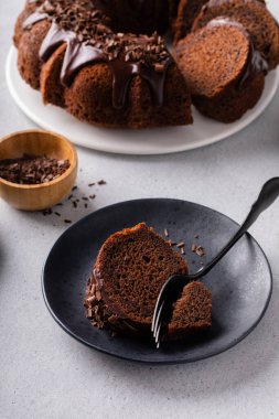 Chocolate cake baked in a bundt pan with chocolate ganache glaze and chocolate curls sliced